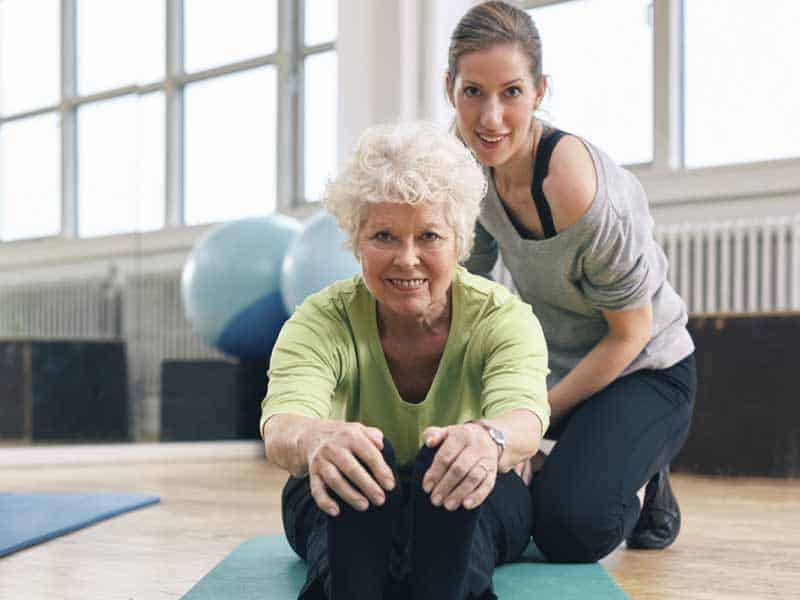 personal trainer helps senior stretch during one-on-one session