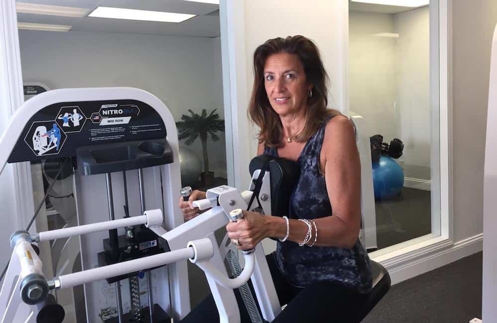 Gail row woman using strength training machine in private fitness studio