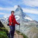 woman hiking on path in front of tall rocky mountaintop