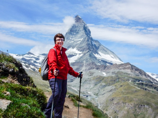 woman hiking on path in front of tall rocky mountaintop