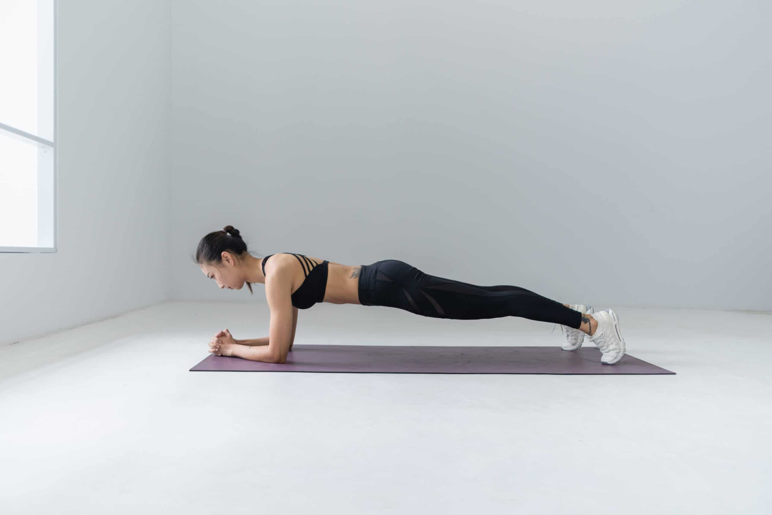 Woman in a plank position on a purple yoga mat.