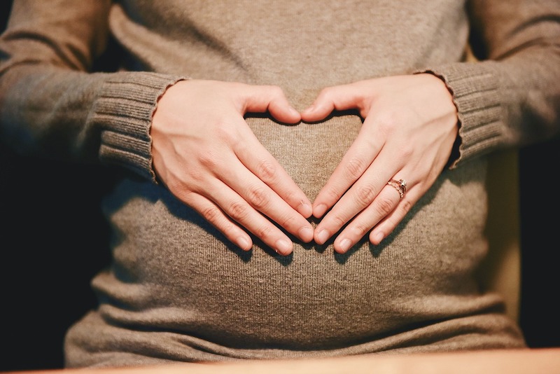 hands in shape of heart over pregnant belly