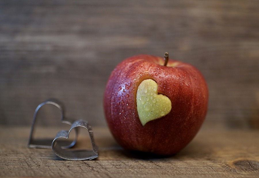 Two mini heart cookie cutters and an apple with a heart shape cut out of it.