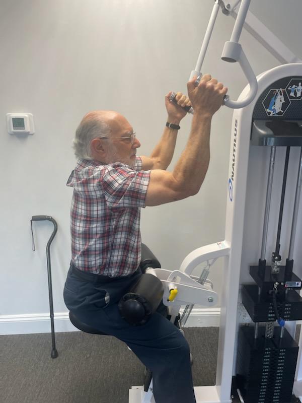 Man using a pulldown exercise machine in an indoor gym.