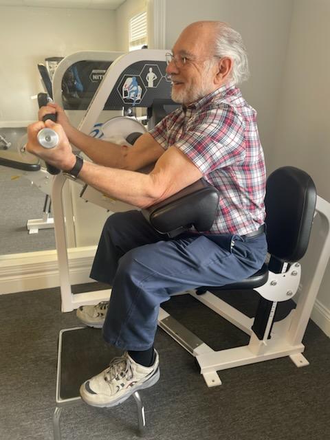 Older man using a piece of exercise equipment at an indoor gym.